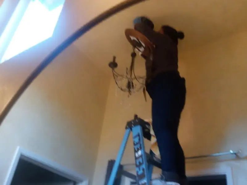 Electrician installing a chandelier in a Compton residence